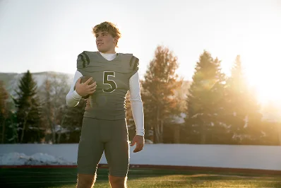 joueur de football américain tenant le ballon sur le terrain au coucher du soleil